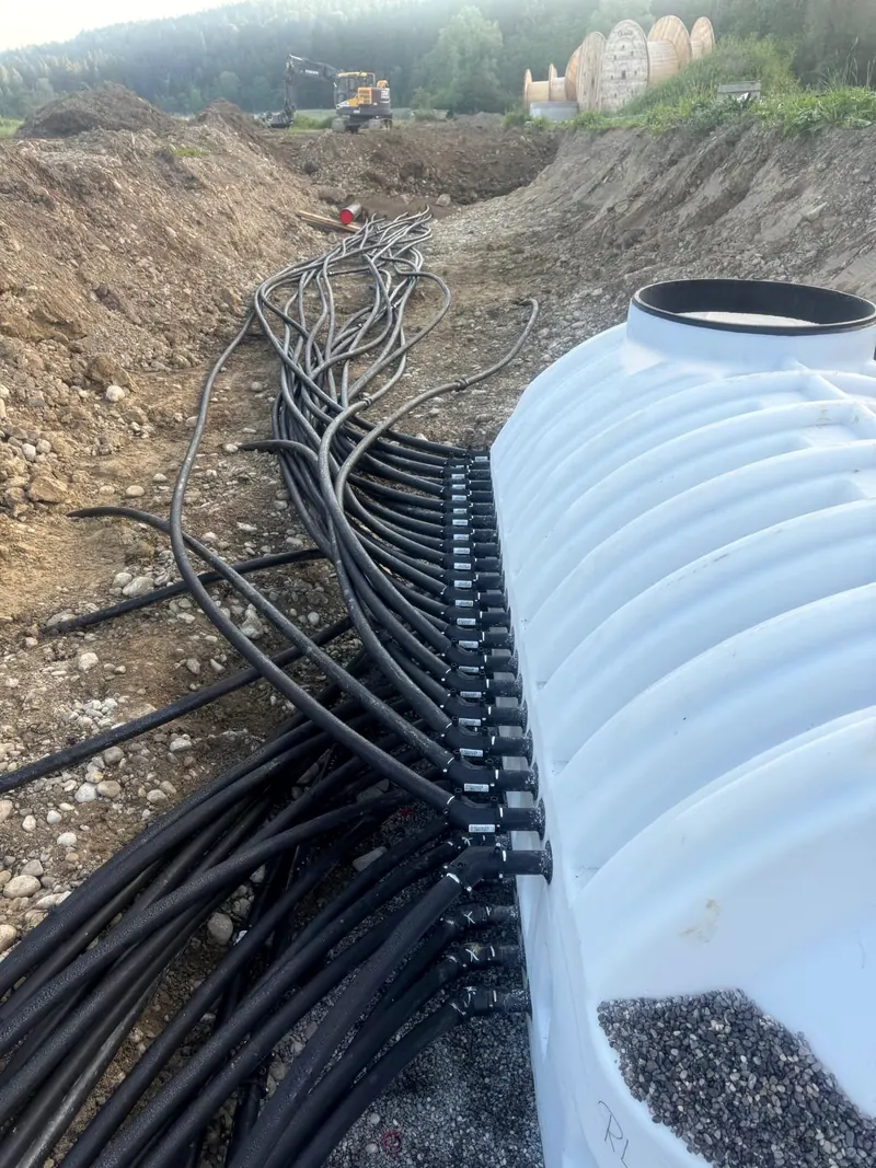 Verteilerschacht mit vielen angeschlossenen PE-Leitungen auf einer Baustelle